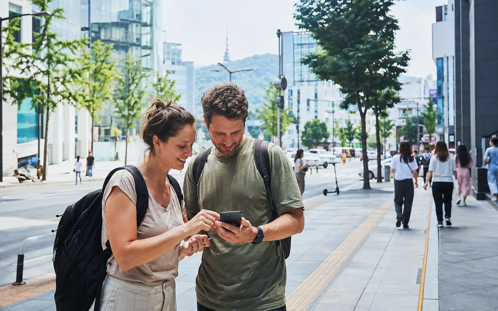 International visitors checking a smartphone while navigating a street in Seoul
